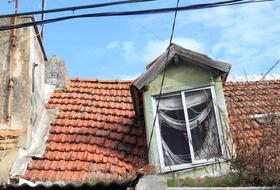 Old house, with the window, in Trafaria, Lisbon, Portugal, at blue sky with white clouds on background