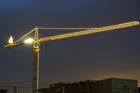 Crane with the driver's cab, with the colorful lights, in the evening with the colorful sunset