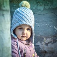 serious Baby girl in winter clothing at wall background , Portrait
