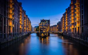 yellow illumination of multi-storey buildings on the canal