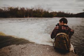 a man with a camera on the river bank