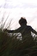 silhouette of a boy in the grass on the beach