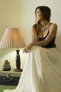 attractive young Woman sits near Lamp indoor