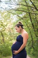 young Pregnant Woman posing at summer forest