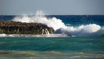 the wave crashes on the rocky shore