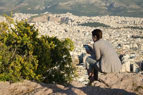 girl reading on Areopagus Hill in view of city, Greece, Athens