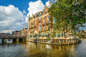 open air cafe around facade of historical building on canal, netherlands, Amsterdam