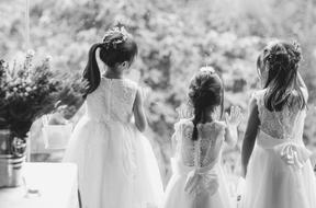 Black and white photo of the kid girls, in the dresses, near the plants