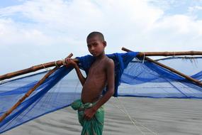 dark skin child boy posing at blue Fishing net