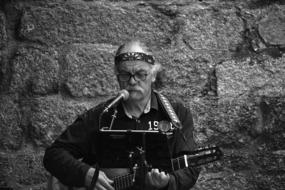 black and white photo of a street guitarist against a stone wall