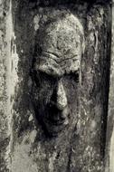 male Face carved on aged tombstone