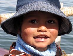 Cute child in denim hat, in sunlight, among the water