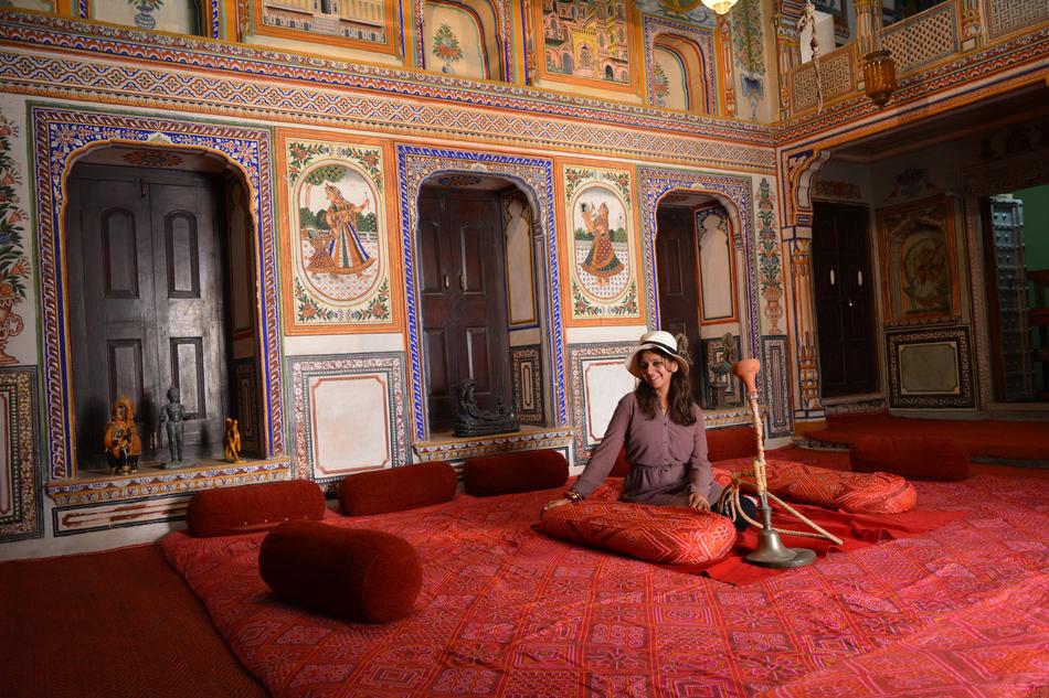 young Girl sits on red carped in Traditional Hukka room