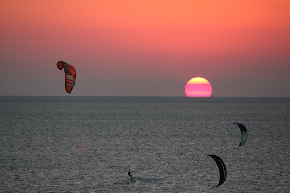 people on parachutes against the background of the sea with the sun