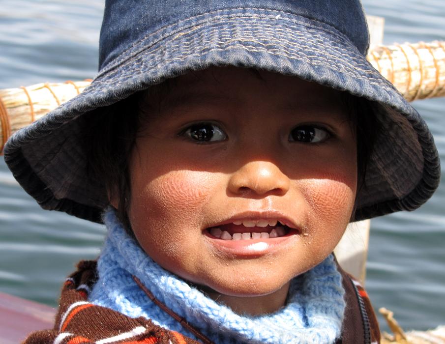 Cute child in denim hat, in sunlight, among the water