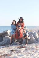 mother with children on large rocks on the coast