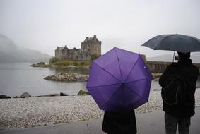 people standing on the beach with umbrellas