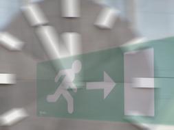 green exit sign with a clock in the background