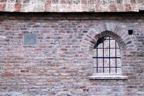 grated window in old brick wall