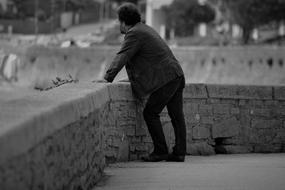 Man standing at stone fence in city