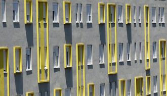 gray building facade with yellow decorative elements on the windows