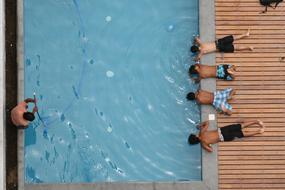 kids laying on edge of swimming pool, top view