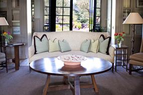 sofa with cushions and a round wooden table in the living room