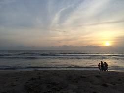 photo of a family on the beach against the background of the evening romantic sky