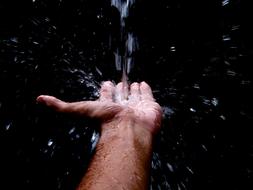 Water jet pouring on male hand
