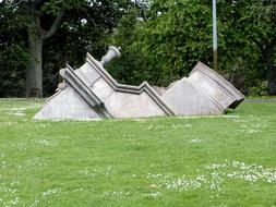 Old sculpture building in the beautiful, green grass meadow, with white flowers, near the green trees