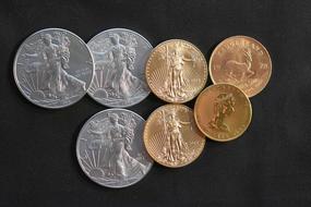 Close-up of the colorful, shiny metal coins with images, on the black surface