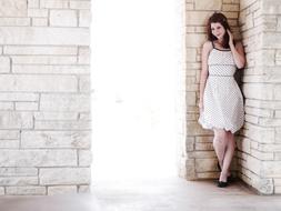 pretty young Girl in White dress posing at brick wall