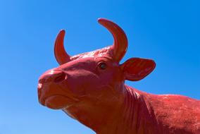 statue of a red cow on a blue sky background