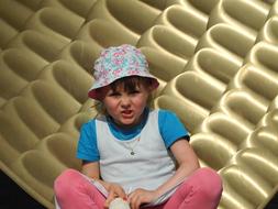 photo of a girl in panama against a background of golden sculpture