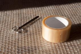 scissors and scotch tape are on a bubble wrap