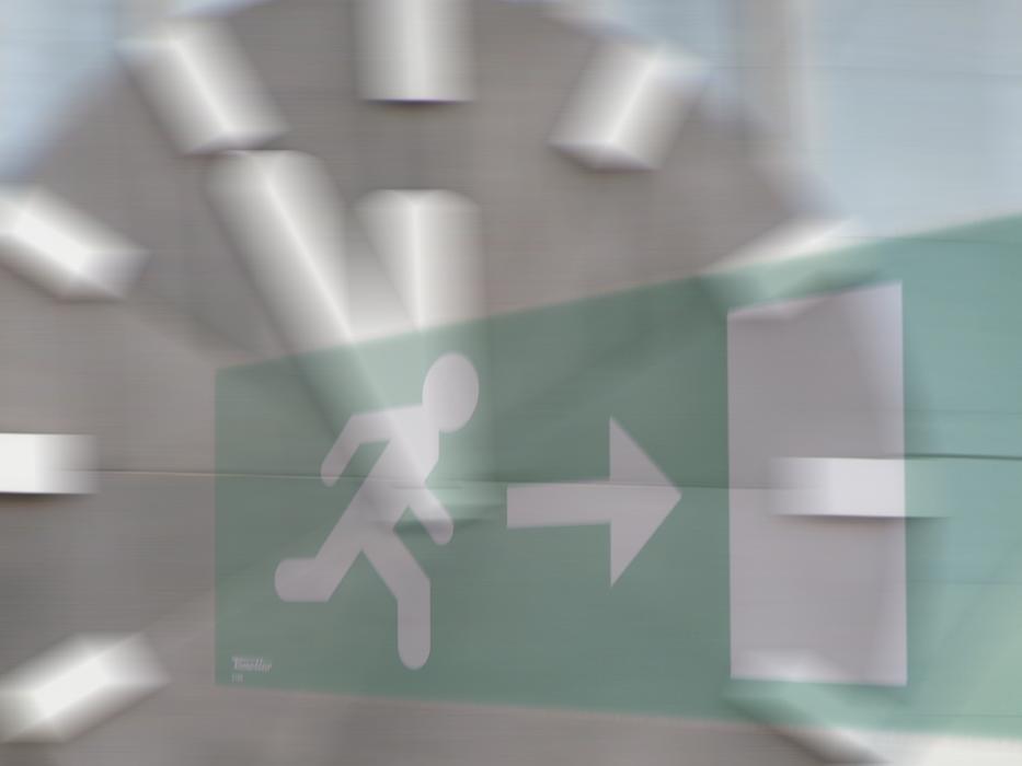 green exit sign with a clock in the background