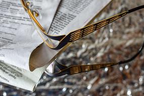 gold glasses lie on a newspaper