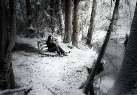 Girl sitting on bench at Winter Snowy forest