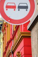 Red, black and white sign, with the cars, on the colorful and beautiful houses