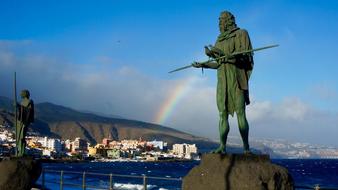 green sculptures with a rainbow in the background