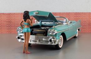 doll in front of a model car