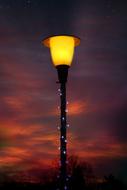 a lamp burning in the night at sunset