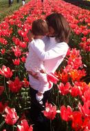 mom with a baby in her arms on a red tulip field