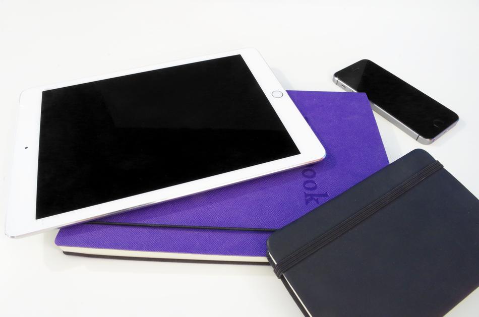 Black and violet notebooks, Ipad and Iphone, on the white surface
