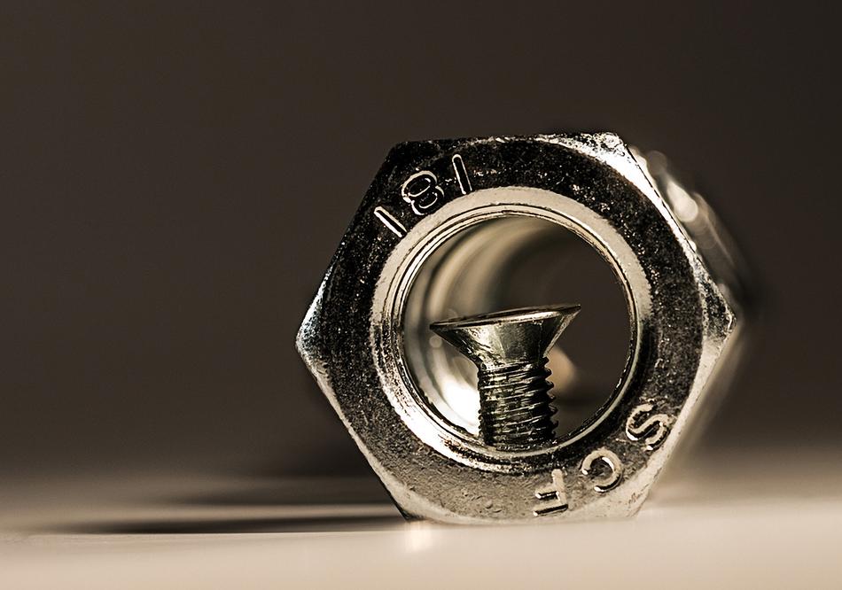Macro photo of the shiny iron nut with signs, with shadow