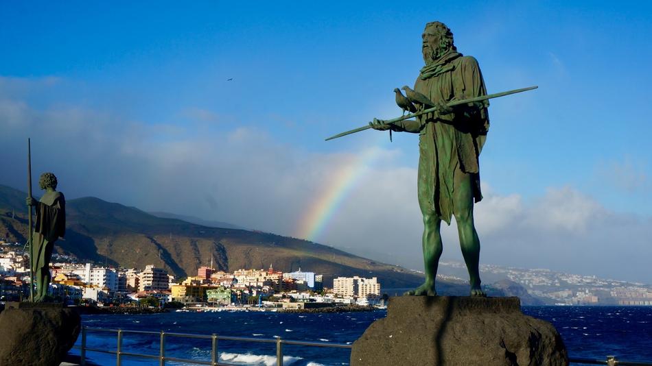 green sculptures with a rainbow in the background