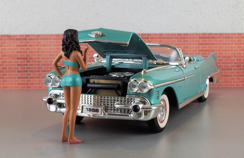 doll in front of a model car