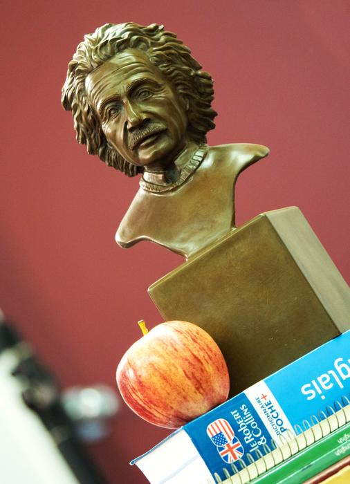 Bronze bust of Einstein near the books with the colorful apple