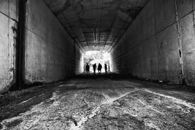 monochrome photo of human silhouettes at end of long Tunnel, Greyscale