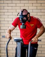 man on an exercise bike wearing a gas mask